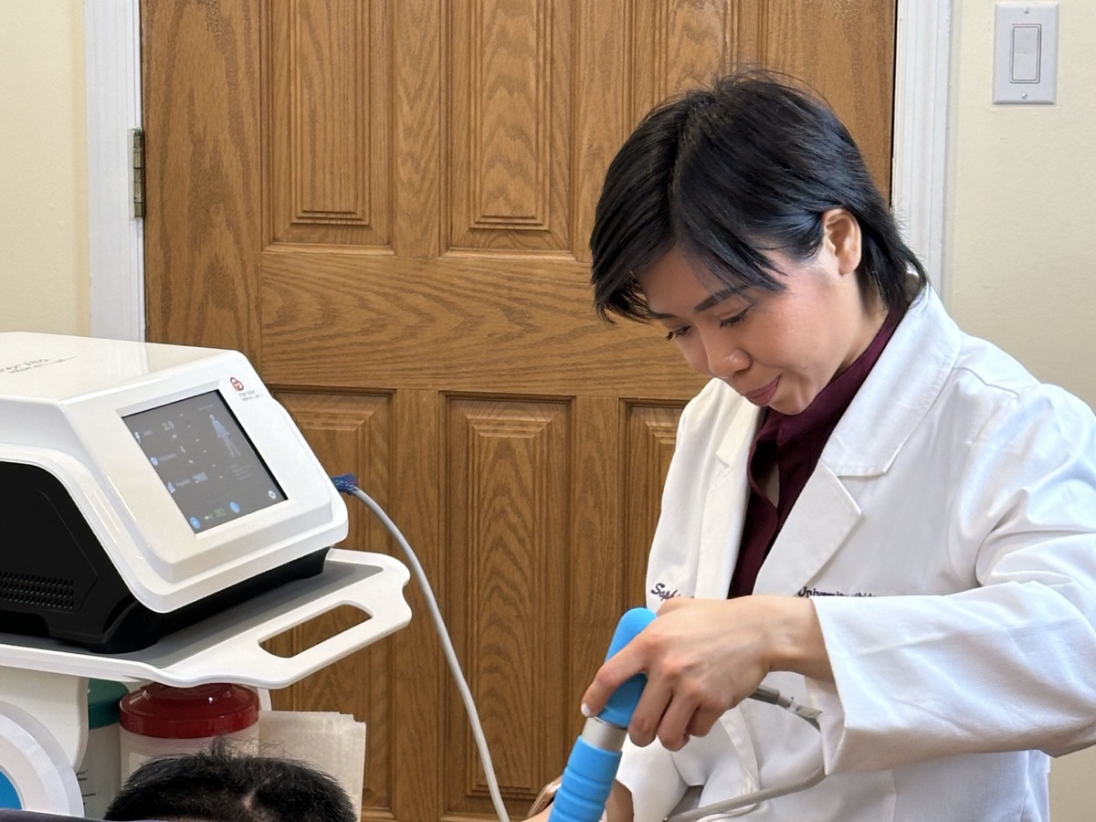 Dr. Sophia Lam applying the extracorporeal shockwave handpiece to a patient's knee