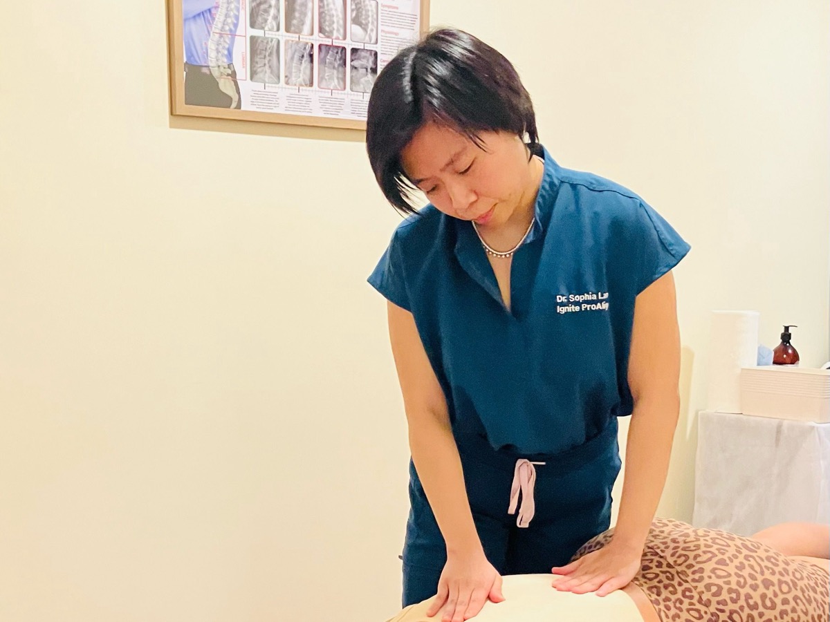 Dr. Sophia Lam performing a hands-on spinal adjustment on a patient at her Bayside clinic